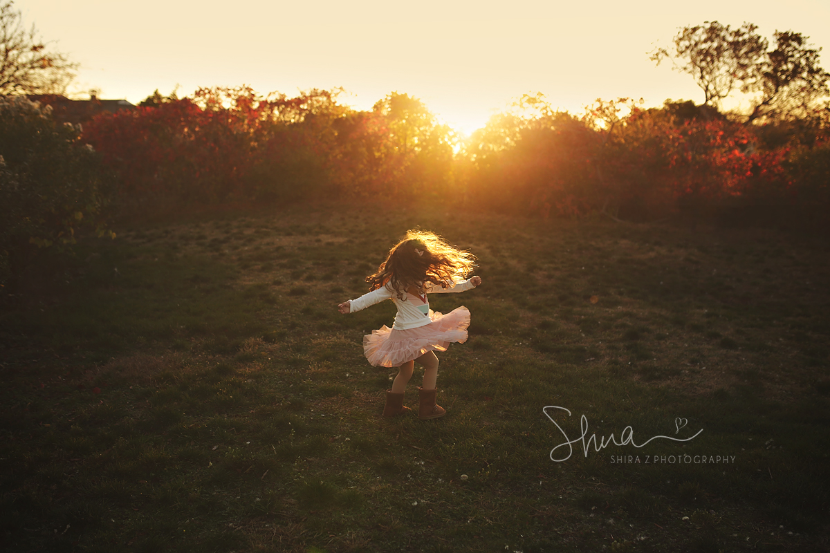 A portrait of a little girlie girl twirling her skirt in the sun at a Long Island preserve. 