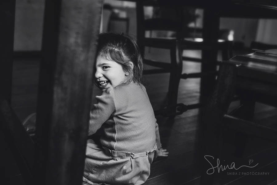 3 year old girl smiling under table at Long Island Family Photography
